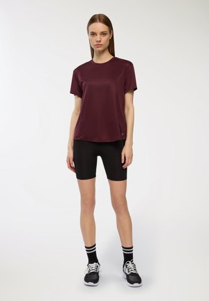 T-shirt sportivo bordeaux a maniche corte, abbinato a pantaloni ciclistici neri. Include calze a righe bianche e nere e scarpe sportive nere.