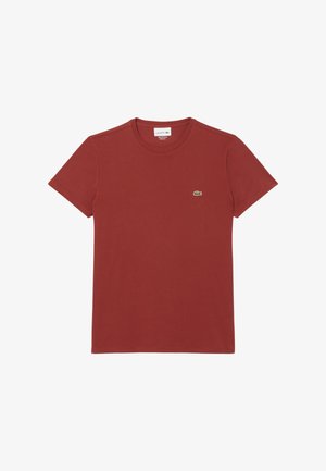 Camiseta de algodón roja con mangas cortas, cuello redondo y un pequeño logo bordado de cocodrilo verde en el lado izquierdo del pecho. Textura suave.