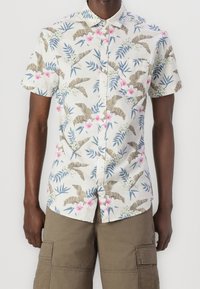 Camisa de manga corta con botones y fondo claro, con un estampado tropical de flores y hojas en tonos verdes, rosas y azules.