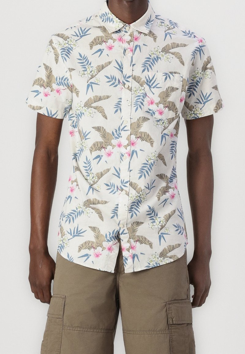 Camisa de manga corta con botones y fondo claro, con un estampado tropical de flores y hojas en tonos verdes, rosas y azules.