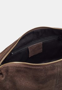 Borsa in suede marrone con apertura zip e cerniera in tonalità oro. All'interno, foderata in tessuto nero con un ulteriore piccolo taschino con zip.