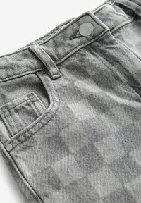 I pantaloni in denim grigio presentano un motivo testurizzato, un bottone argentato in vita e una tasca frontale. Il tessuto mostra un delicato design a quadratini.