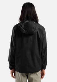 Veste noire imperméable avec capuche, dotée de poignets ajustables et d'un design léger. Texture lisse, style minimaliste et sans marque visible.