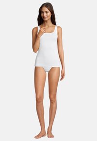Hvid, tætsiddende tanktop med smalle stropper, glat tekstur og firkantet udskæring, parret med matchende hvide trusser.