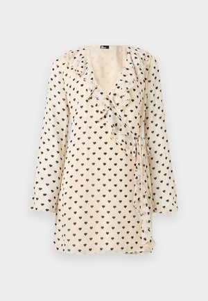 Krēmkrāsas wrap tipa kleita ar garām piedurknēm, melnu sirdiņu rakstu, volānveida kakla izgriezumu un sānu saišu detaļām.