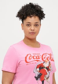 Rosa bomull t-skjorte med Coca-Cola-logo og vintage julenisse grafikk. Korte ermer, rund halsutskjæring, myk tekstur og avslappet passform.
