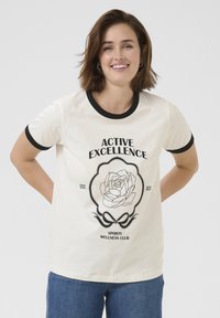 T-shirt en coton blanc avec col et poignets noirs, arborant un design graphique d'une rose et un texte : "CLUB DE BIEN-ÊTRE SPORTIF EXCELLENCE ACTIVE."