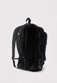 Mochila preta com parte traseira em malha almofadada e alças ajustáveis. Apresenta compartimentos com fecho de correr e detalhes texturizados para maior detalhe.