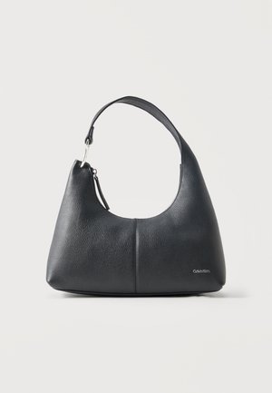 Sac à main en cuir noir texturé avec une seule bandoulière et une fermeture éclair, avec un petit logo Calvin Klein en bas à droite sur le devant.