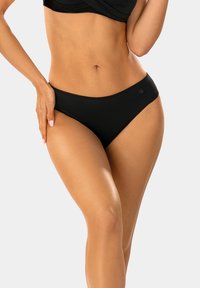 Czarne majtki bikini wykonane z gładkiego materiału, o prostym, niskim kroju, bezszwowych krawędziach i małym logo po lewej stronie.