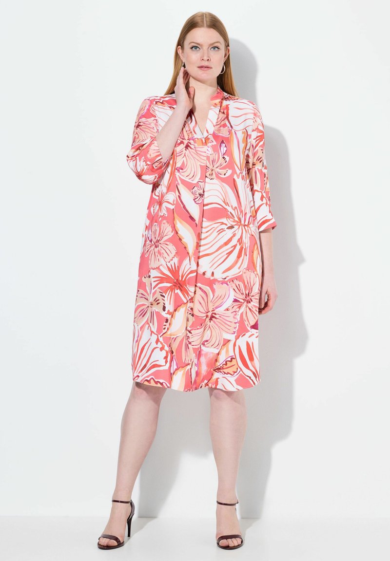 Blommig knälång klänning i rosa nyanser med trekvartsärmar, lätt tyg, V-ringning och knappdetaljer. Stylar med svarta klackar.