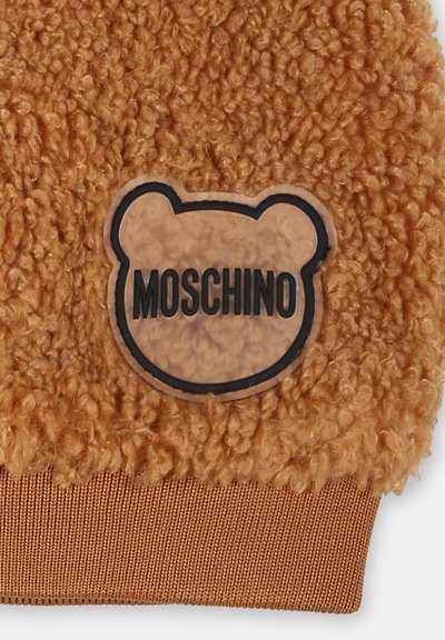Tessuto arancione e morbido con una superficie testurizzata presenta un logo Moschino a forma di orso in nero su uno sfondo trasparente. Bordo elastico marrone nella parte inferiore.