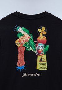 Černé tričko s barevným potiskem zobrazujícím baterku, sendvič, lano, listovou zeleninu, krabičku s džusem, výstražný znak, jablko s větrákem nahoře a text "Gita survival kit."