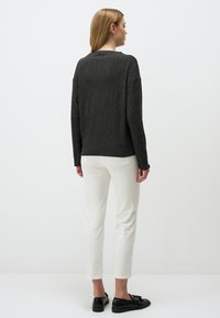 Pull en tricot gris fonc�é avec un motif en relief en forme de diamant ; associé à un pantalon blanc slim-fit et des chaussures noires à enfiler.