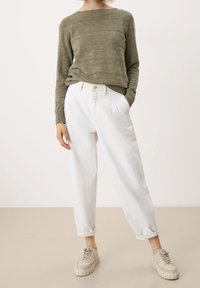 Pull tricoté vert olive à rayures horizontales ; pantalon blanc taille haute avec plis ; baskets plateforme beiges à lacets.