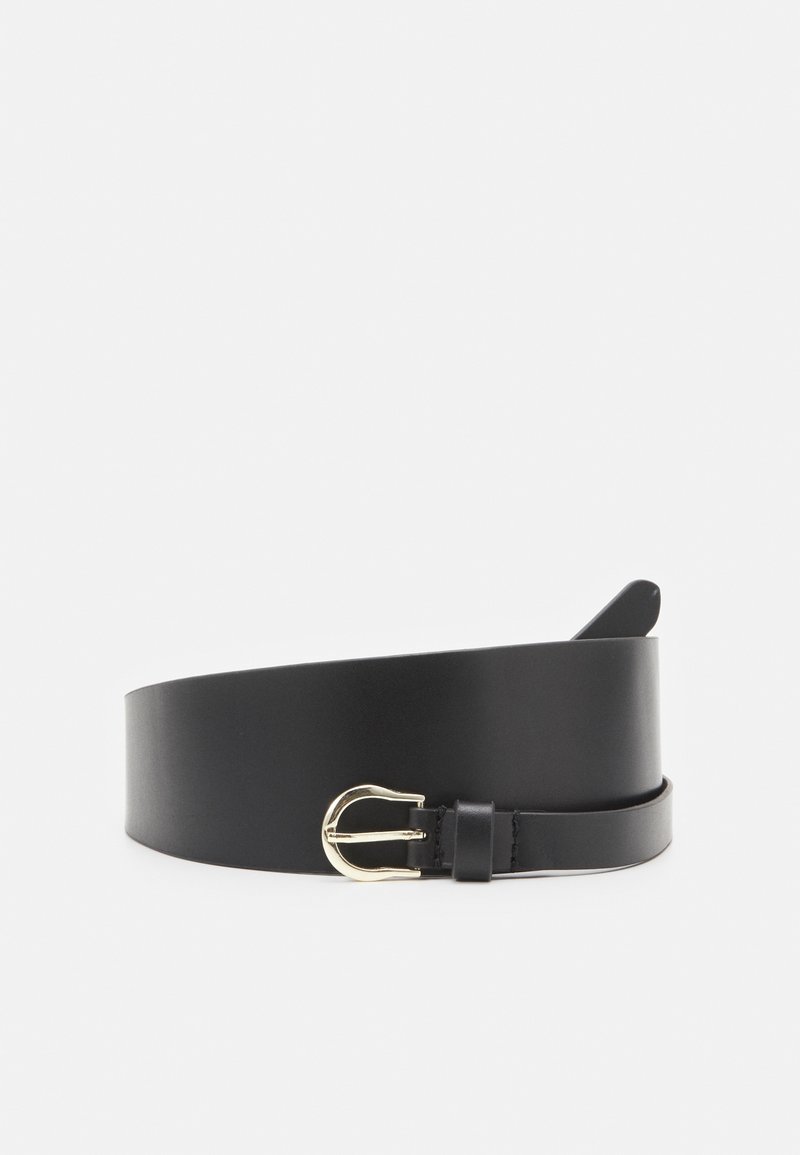 Ceinture en cuir noir enroulée avec une petite boucle métallique dorée incurvée sur fond blanc.