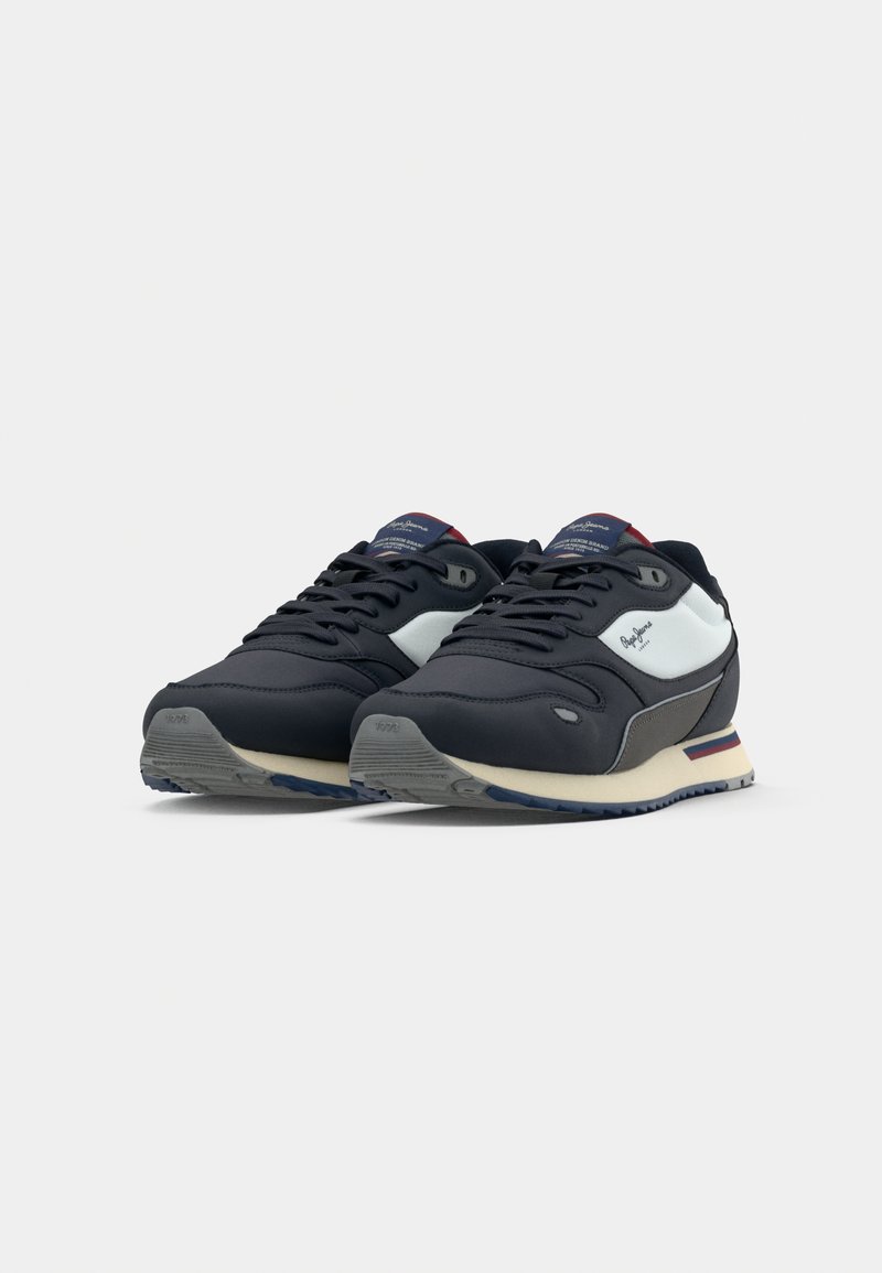Zapatillas deportivas azul marino con un material superior suave, acentos laterales blancos, media suela gris y suela azul contrastante.