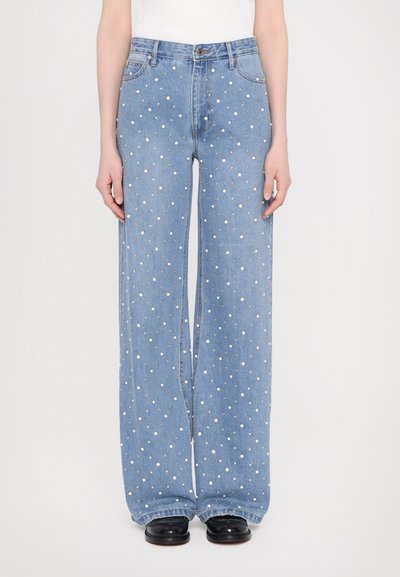 Jeans a gamba larga di colore blu chiaro con un motivo a pois bianchi e accenti metallici. Realizzati in denim con un classico design a cinque tasche.