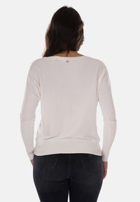 Pullover bianco a maglia con maniche lunghe, vestibilità comoda e un piccolo logo sul retro. Morbido al tatto e con polsini a coste.