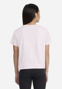 T-shirt rose courte avec col rond et manches courtes, en tissu doux. Le dos est uni avec une coupe décontractée et sans motifs visibles.