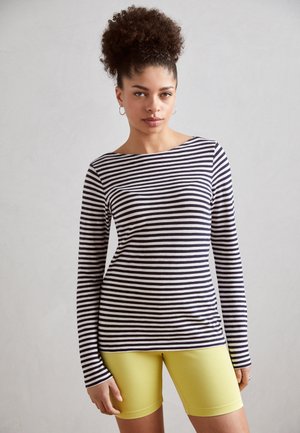 Chemise à manches longues rayée en coton bleu marine et blanc, assortie à un short de cyclisme jaune. Texture lisse, encolure ronde, silhouette ajustée.