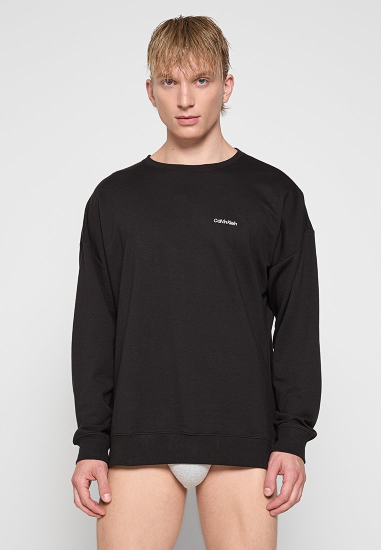 Felpa nera a maniche lunghe in cotone con collo a giro, caratterizzata da un logo bianco di Calvin Klein sul petto e una vestibilità comoda.