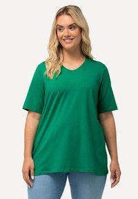 Grünes Kurzarm-T-Shirt aus weicher Baumwolle. Mit Rundhalsausschnitt, lockerer Passform und glatter Textur. Ideal für die Freizeit.