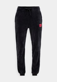 Sorte velour joggebukser med elastisk midjebånd, snøring, sidelommer og tettsittende mansjetter. Har et rødt merke på venstre lår.