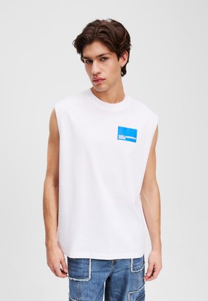 Weißes ärmelloses T-Shirt aus Baumwolle mit einer blauen rechteckigen Tasche, die das Logo "KARL LAGERFELD JEANS" in weißem Text zeigt.