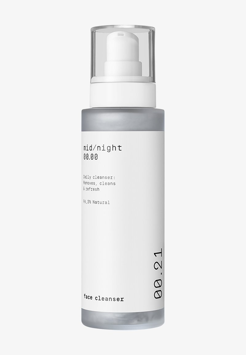 Doorzichtige plastic fles met een witte pomp, grijze basis, minimalistisch ontwerp. Etiket vermeldt "mid/night" en "gezichtsreiniger," 96,2% natuurlijke ingrediënten.
