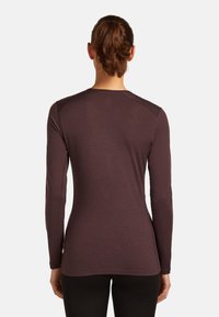 Langarmshirt in donkerburgundy, gemaakt van zachte, lichtgewicht stof. Heeft een ronde hals en een aansluitend ontwerp met minimale stiksels.