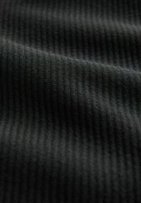 Close-up of black ribbed fabric showing textured, parallel raised lines and soft folds.