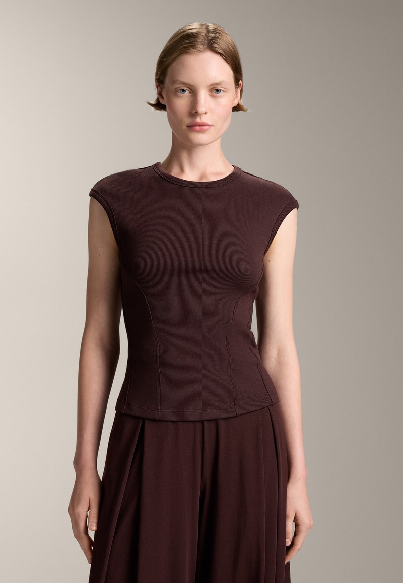 Burgundyröd figurnära ärmlös topp i ribbad textur med rund halsringning och böjda sömmar, matchad med en plisserad nederdel.