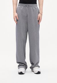 Gray sweatpants made of soft fabric, featuring an elastic waistband with drawstring, wide legs, and two side pockets.