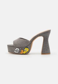 Sandales plateforme grises avec un design à bout ouvert, présentant un dessus en tissu texturé et un talon épais. Détail brodé de Tweety Bird remarquable sur le côté.