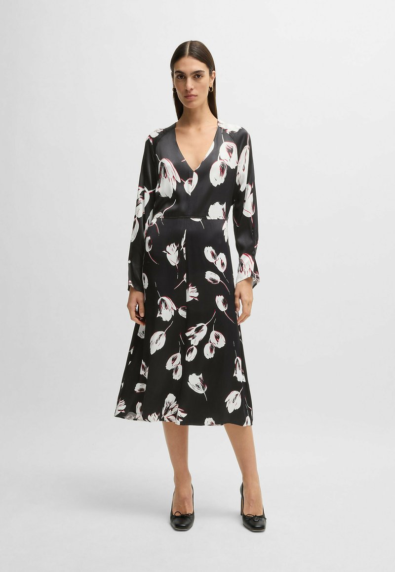 Schwarzes Blumenkleid mit tiefem V-Ausschnitt und langen Ärmeln. Besitzt Muster aus weißen und roten Blumen, eine glatte Textur und eine fließende Midi-Länge.