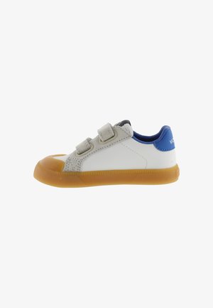 Witte kindersneaker met bruine rubberen zool, twee grijze klittenbandsluitingen en een blauwe hielkraag.