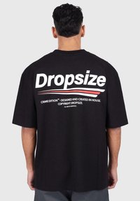 Black cotton t-shirt featuring bold white lettering "Dropsize" and red accents, with a relaxed fit and short sleeves. Back view displayed.