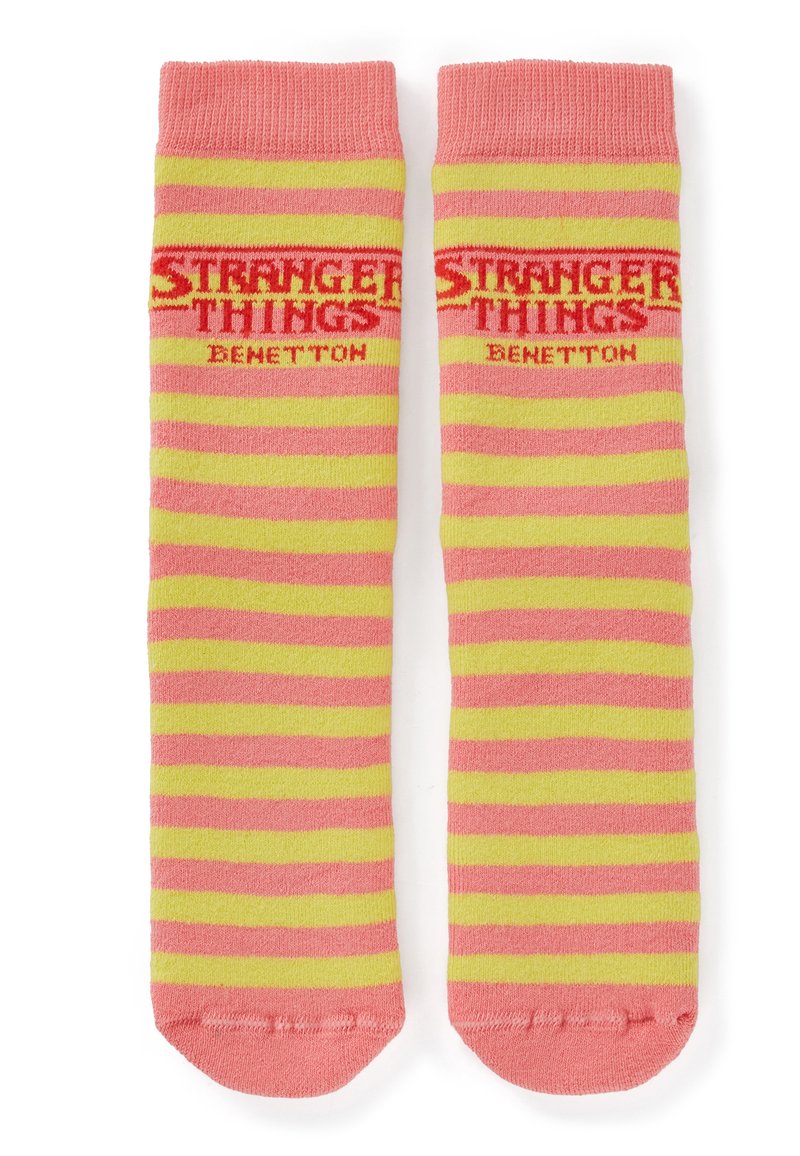 Calzini a righe rosa e gialle con scritte "STRANGER THINGS" e "BENETTON", tessuto lavorato a maglia e polsini a coste con punta arrotondata.