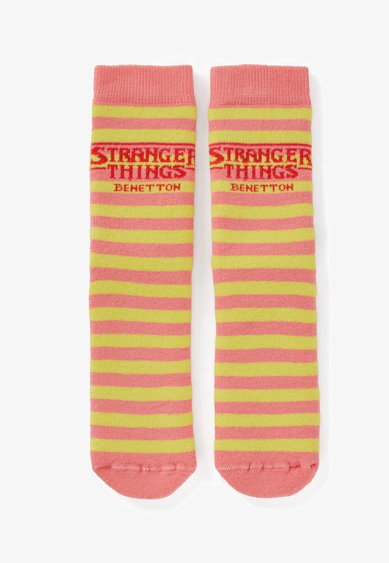 Calzini a righe rosa e gialle con scritte "STRANGER THINGS" e "BENETTON", tessuto lavorato a maglia e polsini a coste con punta arrotondata.