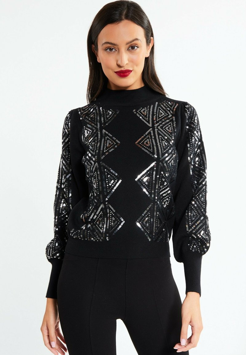 Maglione nero con collo alto, decorato con motivi geometrici in paillettes argentate. Presenta maniche a sbuffo e una silhouette aderente.