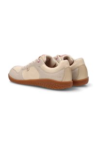 Zapatillas casuales de color beige claro con suelas de goma marrón y ojales de cordones rosa, mostradas desde ángulos trasero y lateral.