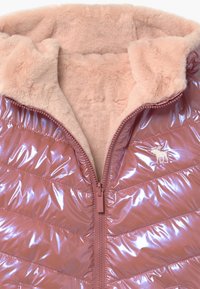 Gewatteerd jack met een glanzende roze buitenkant met horizontale naden, een zachte beige binnenkant en een ritssluiting aan de voorkant.