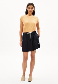 Haut à manches courtes à rayures orange et jaune ; associé à une jupe élastique navy avec poches et cordon de serrage.