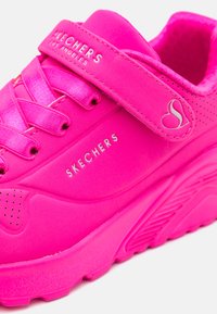 Rózsaszín Skechers sportcipő sima szintetikus felsőrésszel, fűzővel és tépőzárral, perforált díszítésekkel és kontúrozott talpdesigennel.