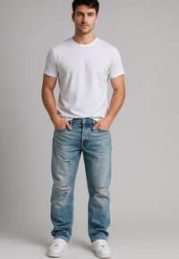 Weißes Kurzarm-T-Shirt, kombiniert mit hellblauen, ausgewaschenen Jeans mit Rissen, abgenutztem Look und weißen Sneakern.