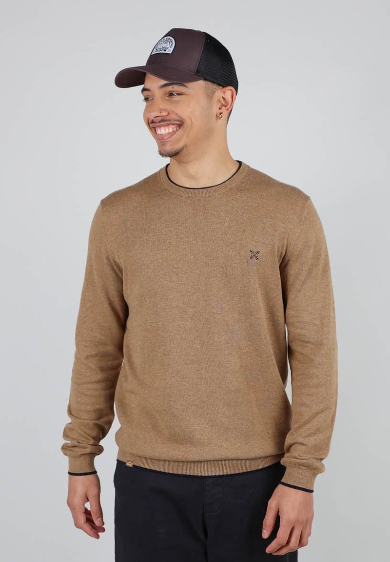 Pull en tricot marron clair avec des manches longues, un col rond, des accents foncés aux poignets et à l'ourlet, arborant un petit logo sur la poitrine.