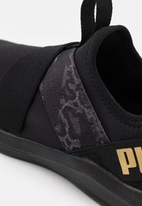 Chaussure de sport noire avec un dessus en tissu extensible et un panneau texturé et à motifs. Comprend un logo bien visible et une languette à l'arrière pour un enfilage facile.