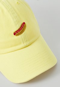 Gelbe Baumwollmütze mit einem gebogenen Schirm, auf der Vorderseite mit einem bestickten Hot-Dog-Design in rot und gelb.
