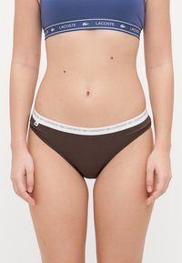 Barna pamut bikini alsó fehér, logóval díszített elasztikus derékkal. Sima tapintású és testhez simuló kialakítás.